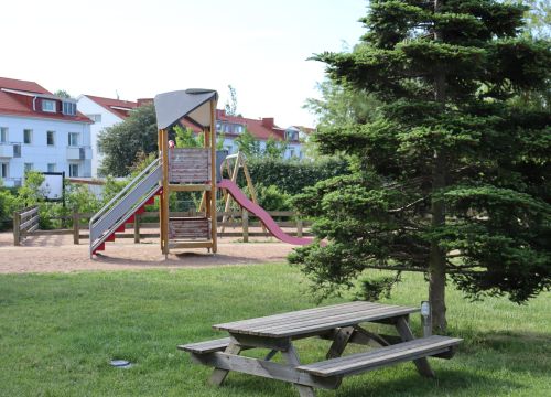 Klätterställning med bord, bänkar och träd i förgrunden