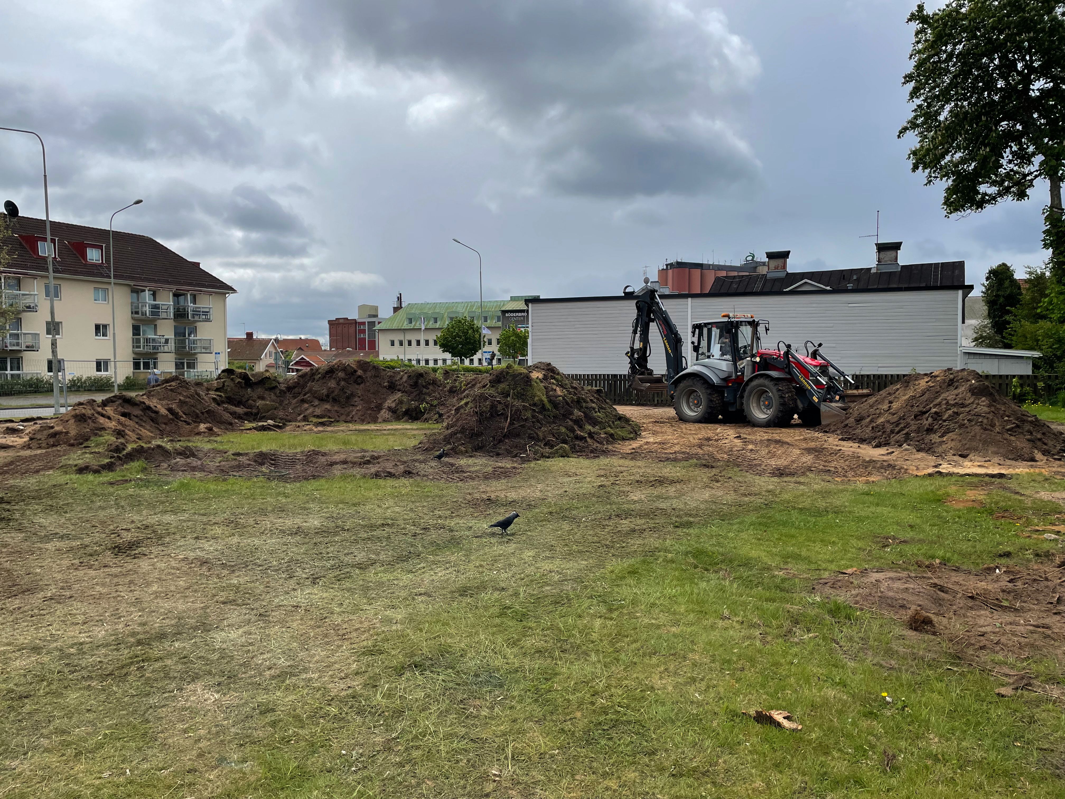 Gräsplätt med jordhögar. En röd traktor står parkerad.