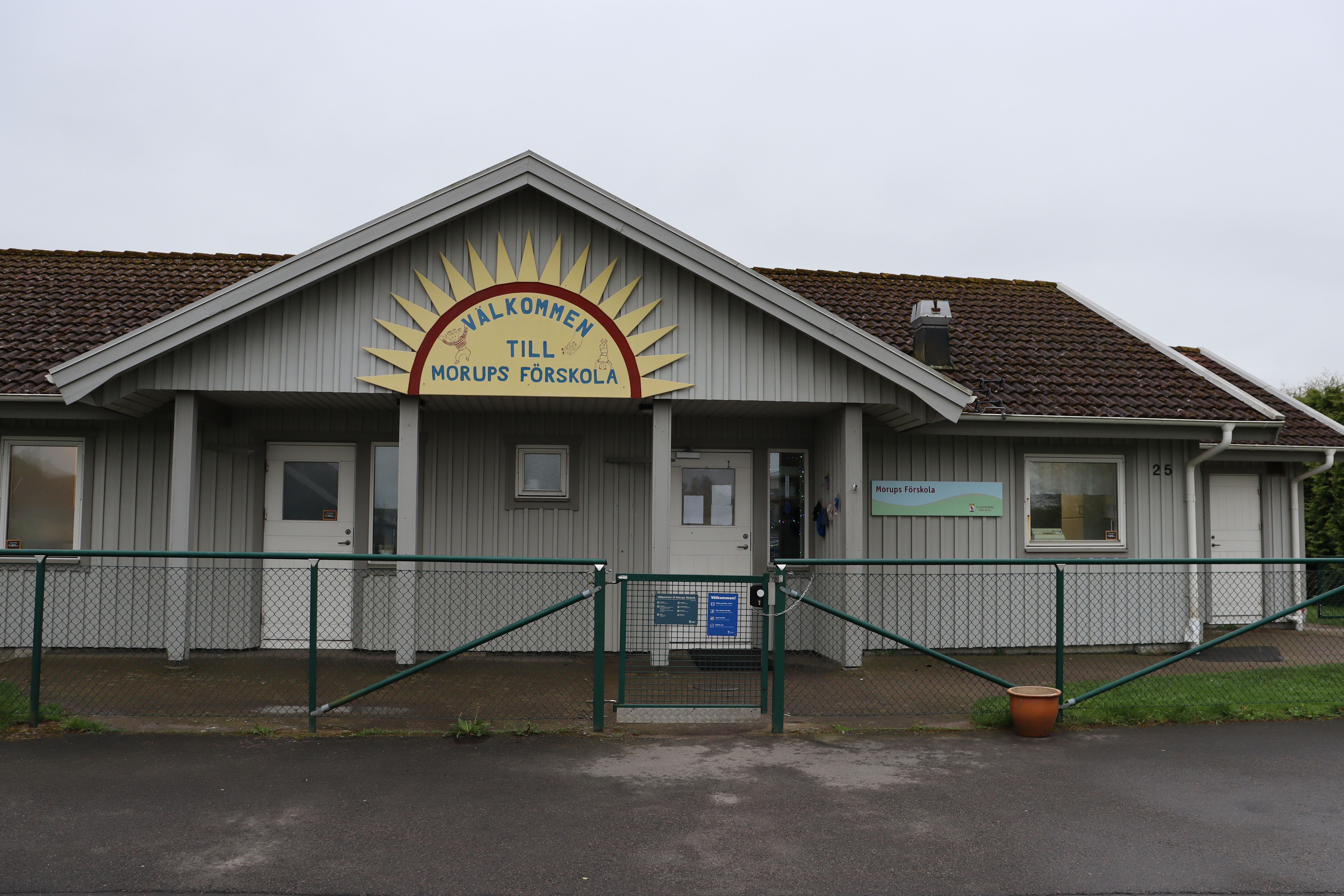 Grå träfasad med förskolans skylt på i form av en gul sol