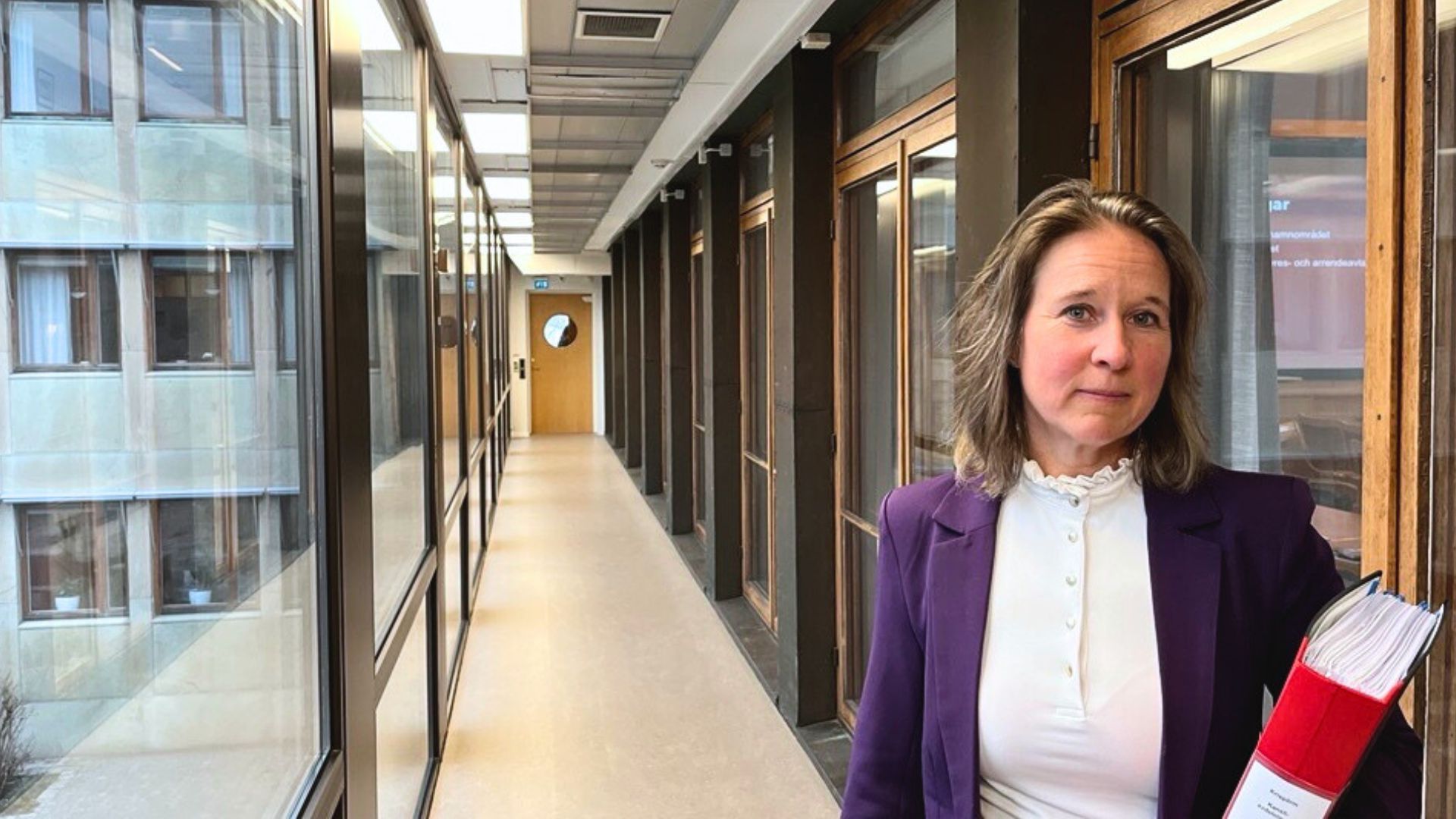 Lena Davidsson i en korridor med en pärm i handen.