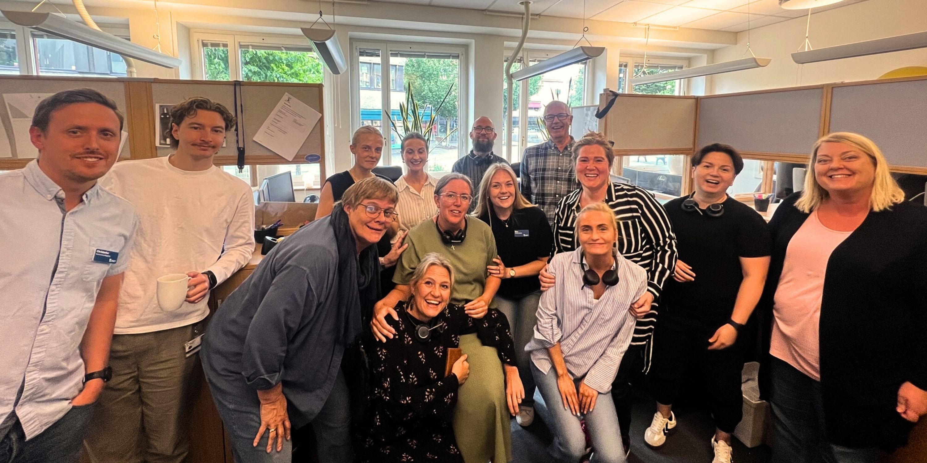 En grupp personer i inomhusmijö. De ser glada ut.