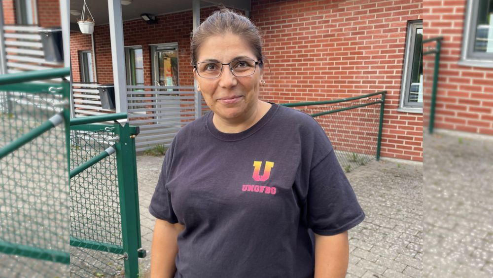 En bild på Ilda. Hon står framför en tegelbyggnad. Hon har en svart Ung FBG-tshirt och neutral min.