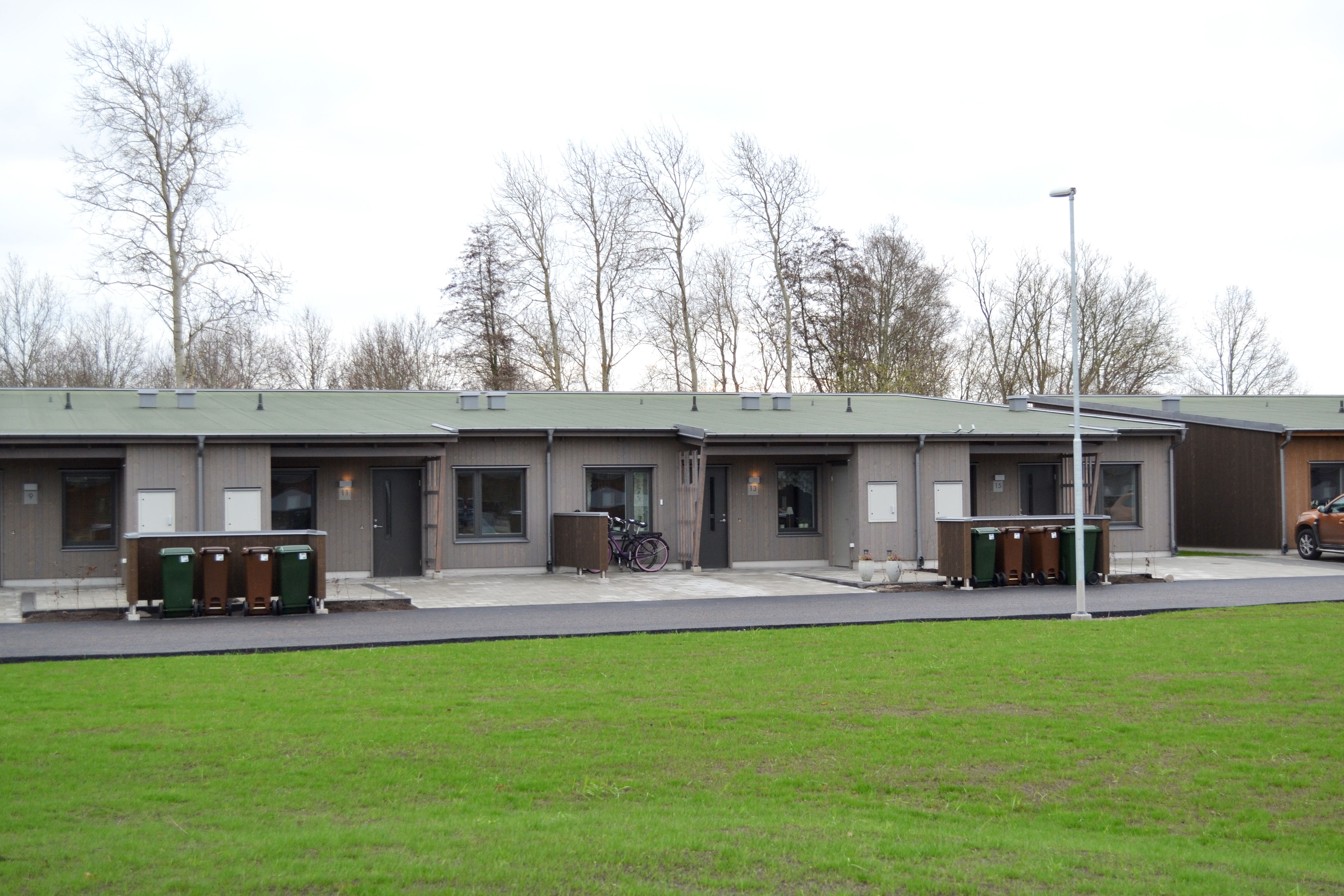 Grå radhus. I förgrunden en gräsmatta.