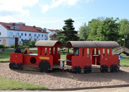 Rött trätåg – gräsplan och träd i bakgrunden