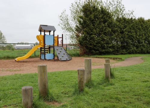 Balansbana på gräs med klätterställning i bakgrunden