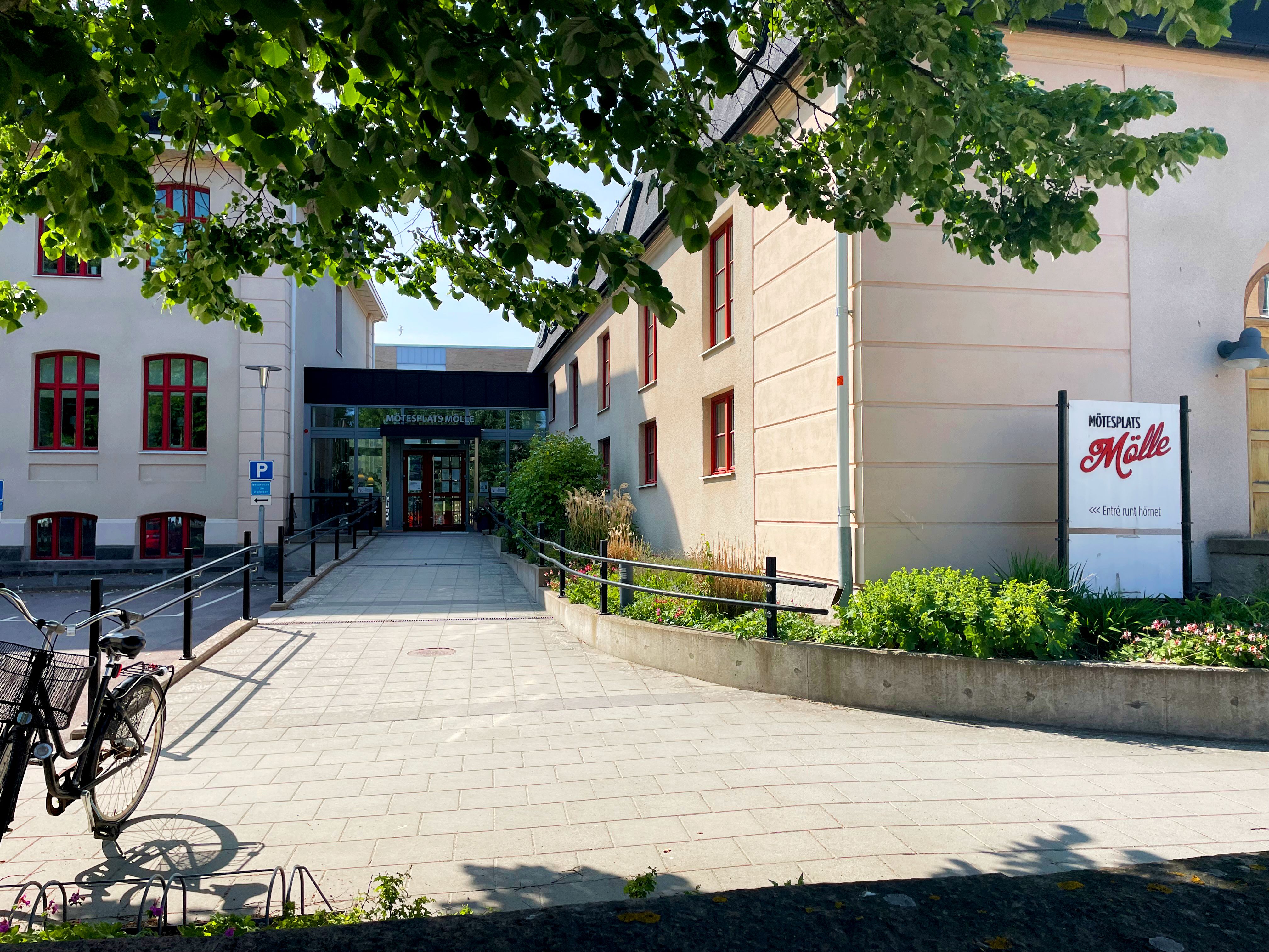 Entrén till Mötesplats Mölle. Solen skiner och i rabatten växer blommor och gröna växter.
