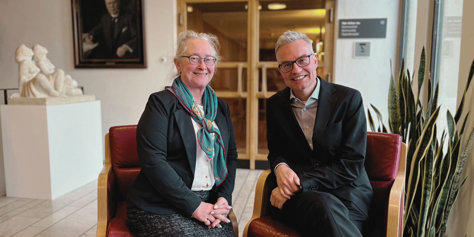 Yen Gunnarsson och Mikael Larsson sitter inomhus. De ler.