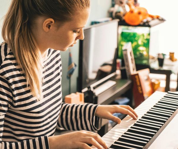 En flicka klädd i svart och vit randig tröja spelar piano