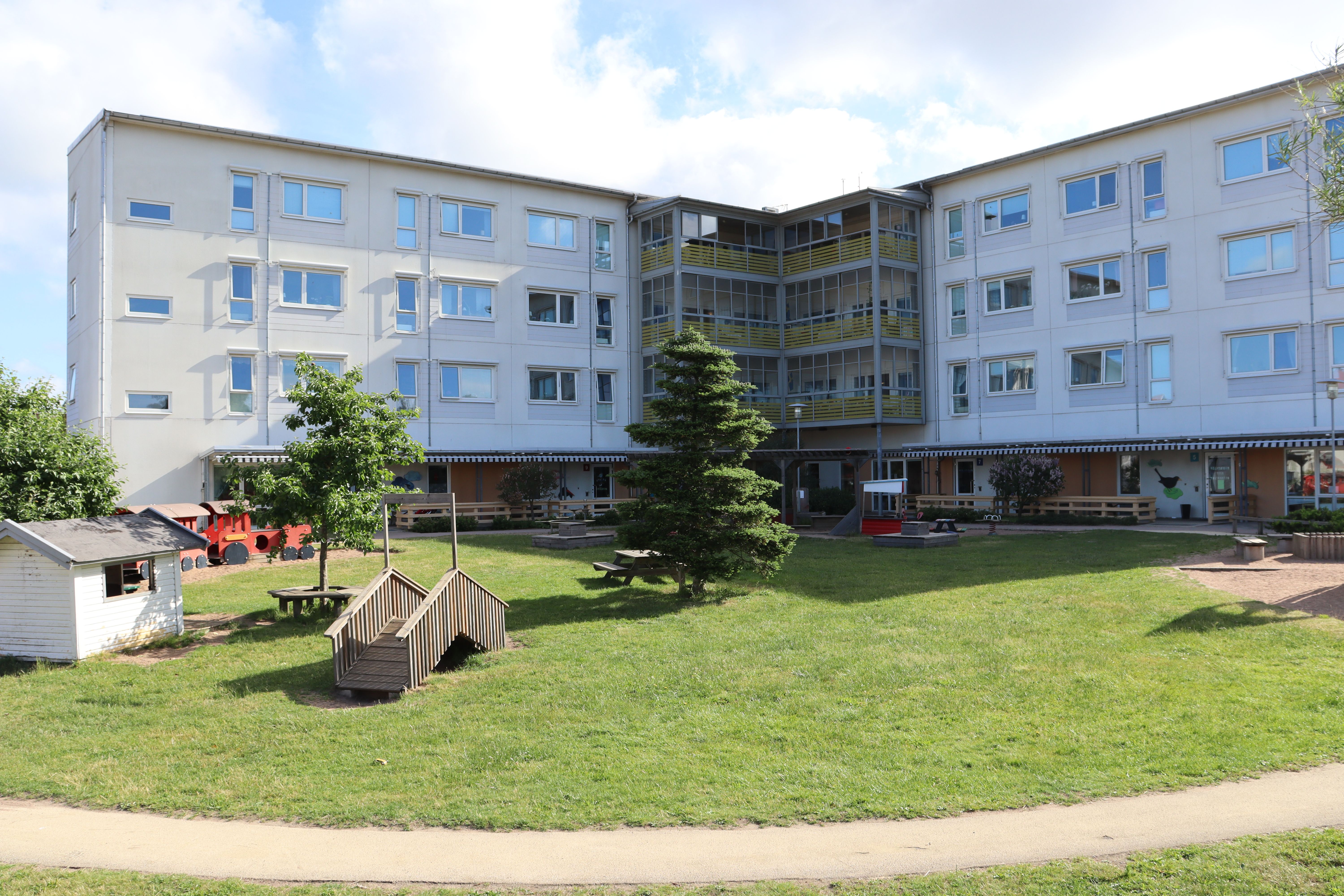 Vit fasad, trevåningshus, gård i förgrunden