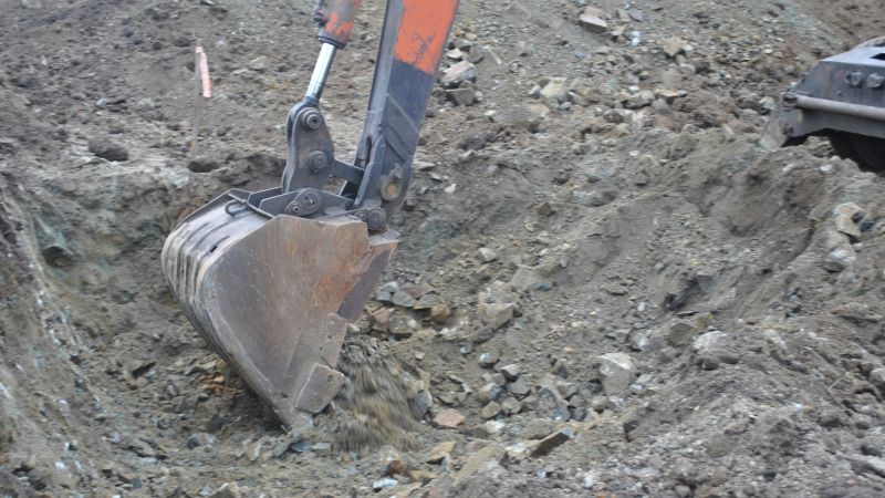 Grävskopa som gräver i grus.