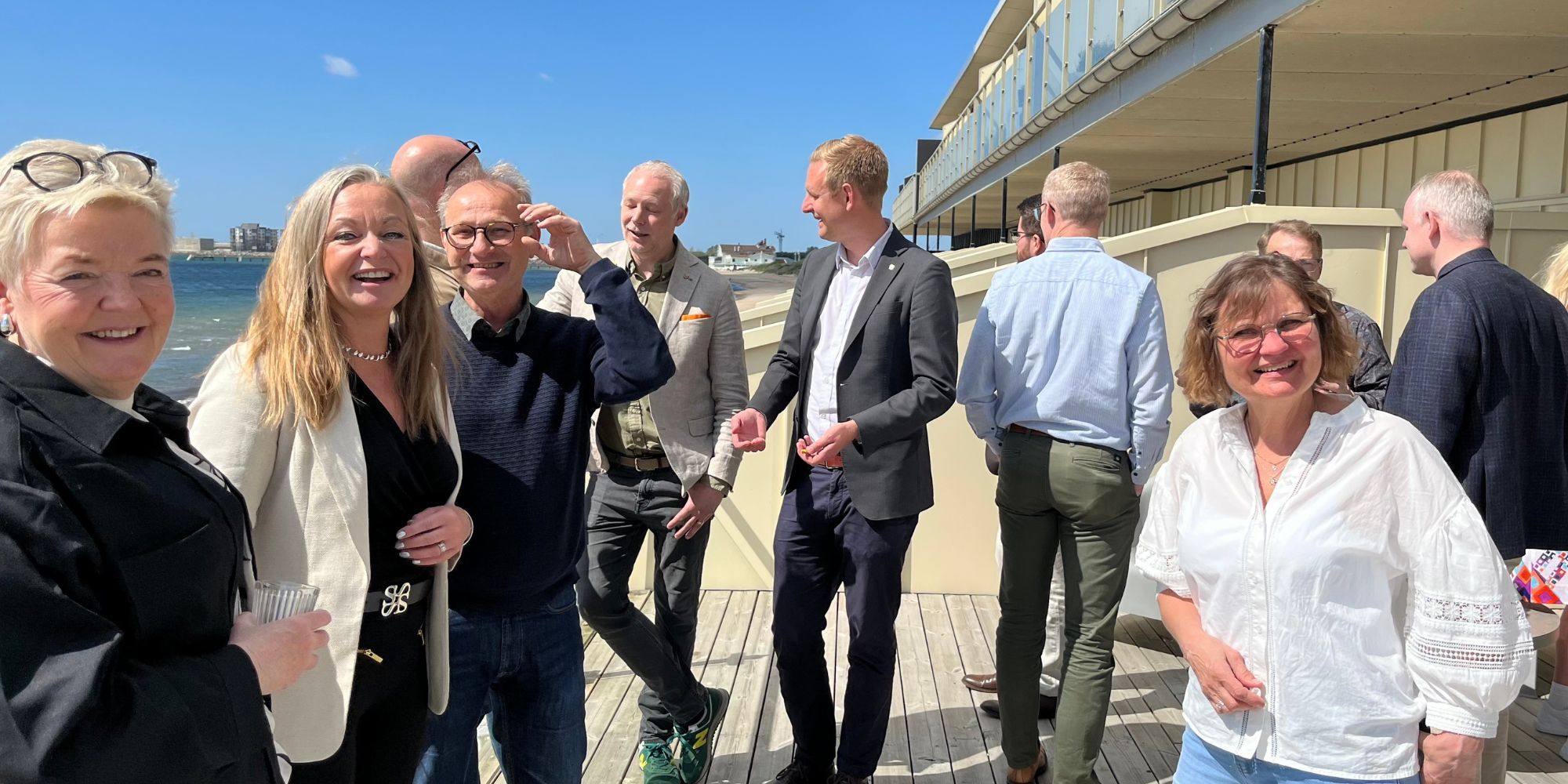 En bild tagen utomhus med många personer som minglar. De ler.