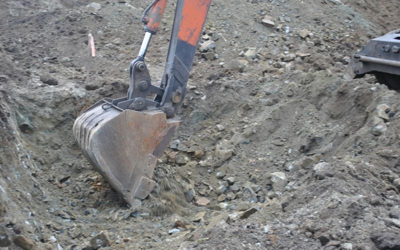 Grävskopa som gräver i grus.