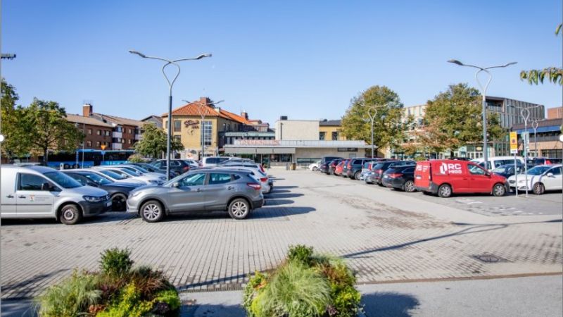 Stortorget i Falkenberg med blå himmel och många bilar parkerade.
