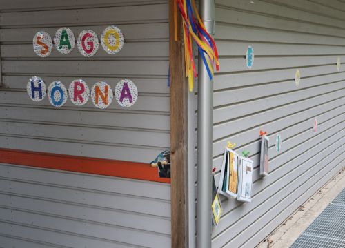 Husknut med texten "sagohörna", färgglada band och häften på väggen