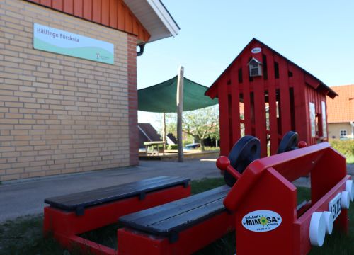 Röd lekbil med lekstuga i bakgrunden