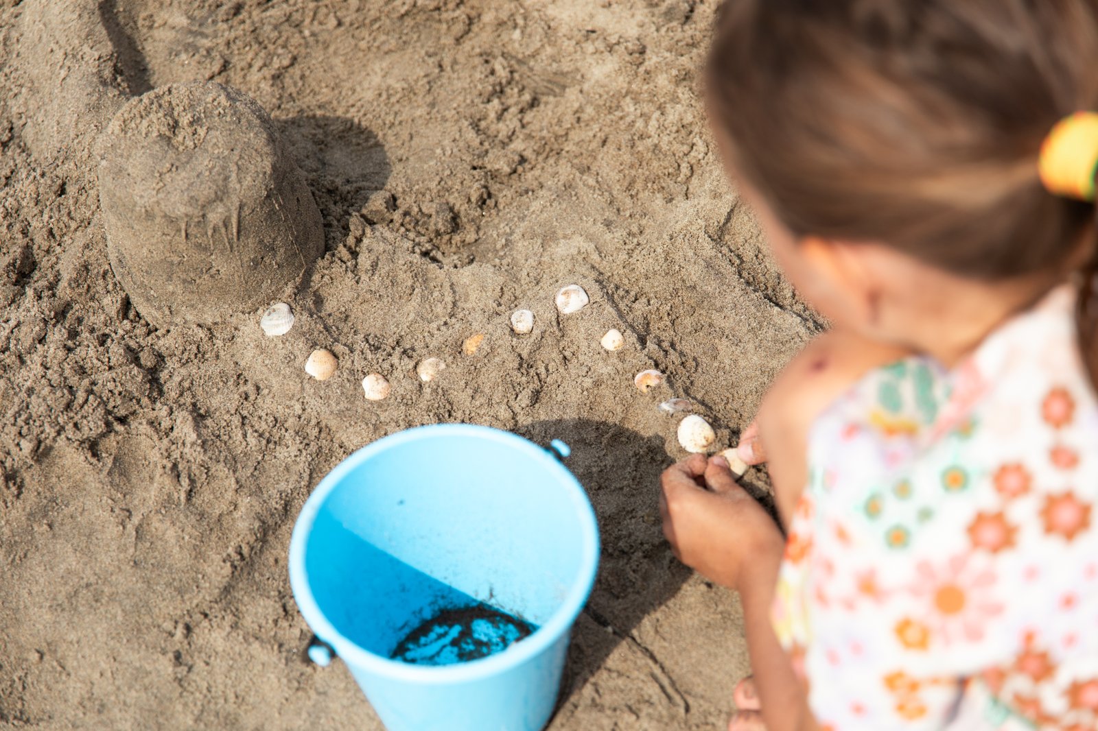 Flicka leker med sand och snäckor
