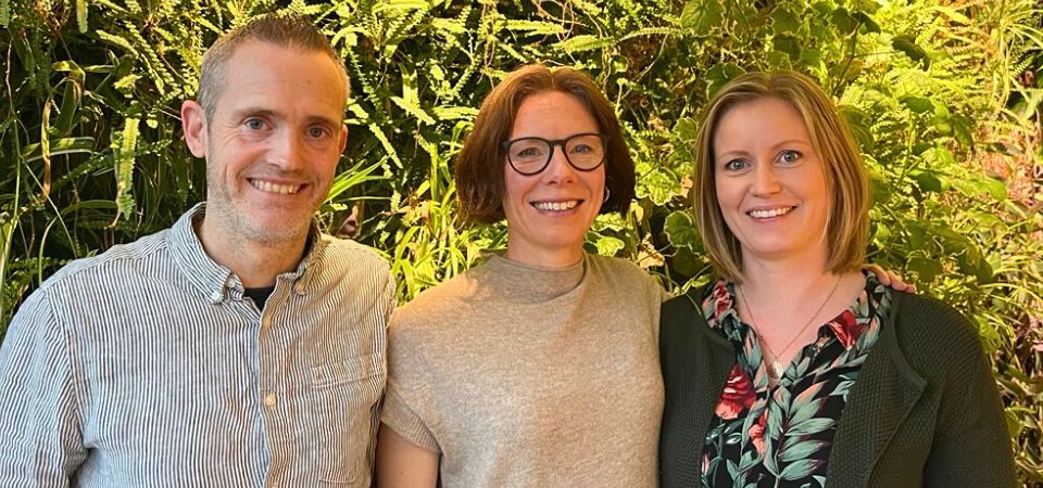 Niklas Grip, delägare och projektledare, Karin Fornell, vd och Erica Hörteborn, arkitekt och hållbarhetssamordnare står framför en grön vägg med växter.