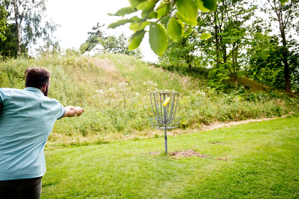 Man som kastar discgolf i korgen