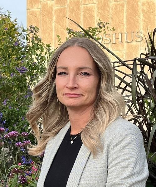 Lotta Jönsson står utomhus med neutral min. Hon bär kavaj.