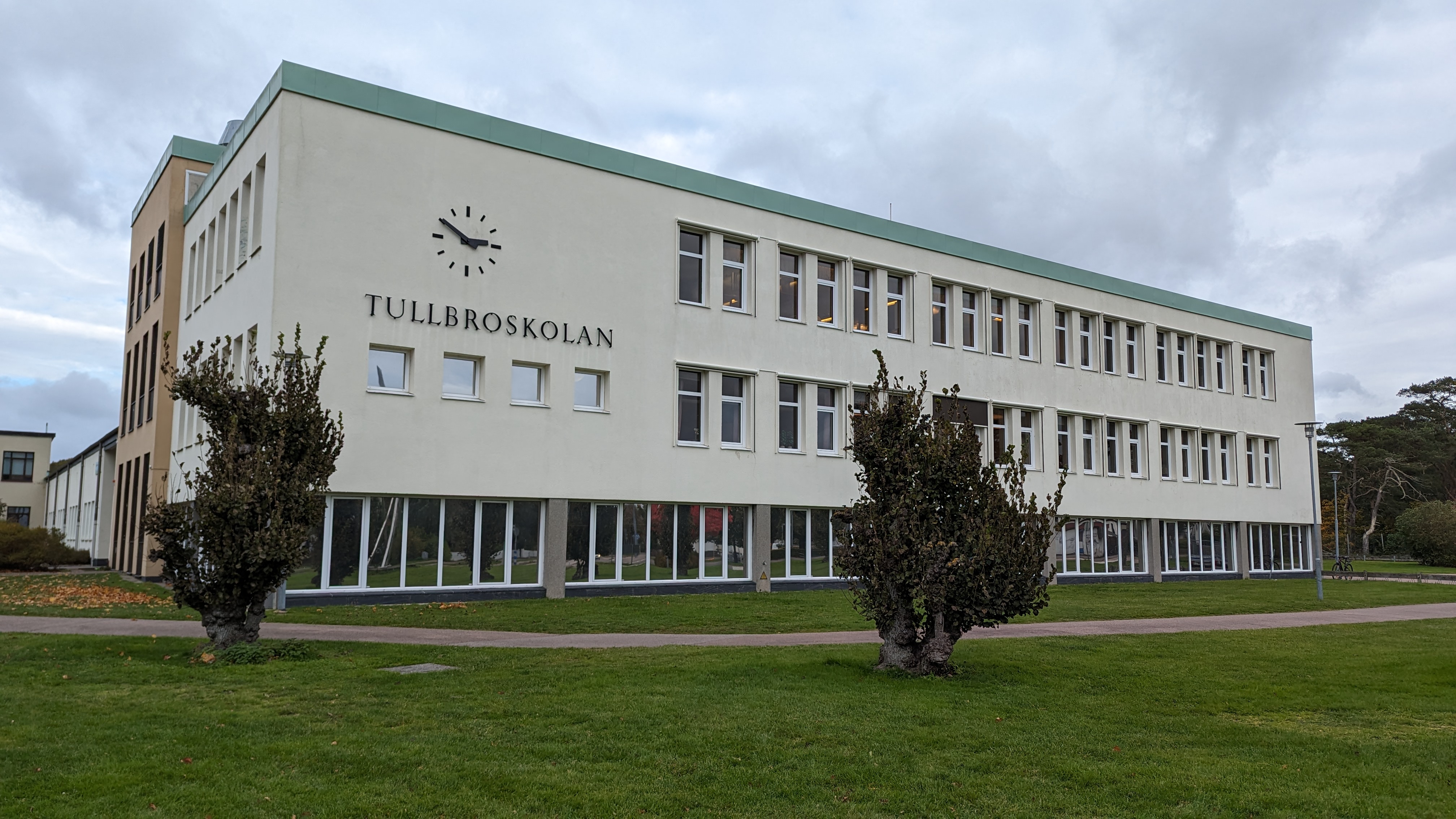 Vitbetongbyggnad med texten Tullbroskolan och en stor klocka.