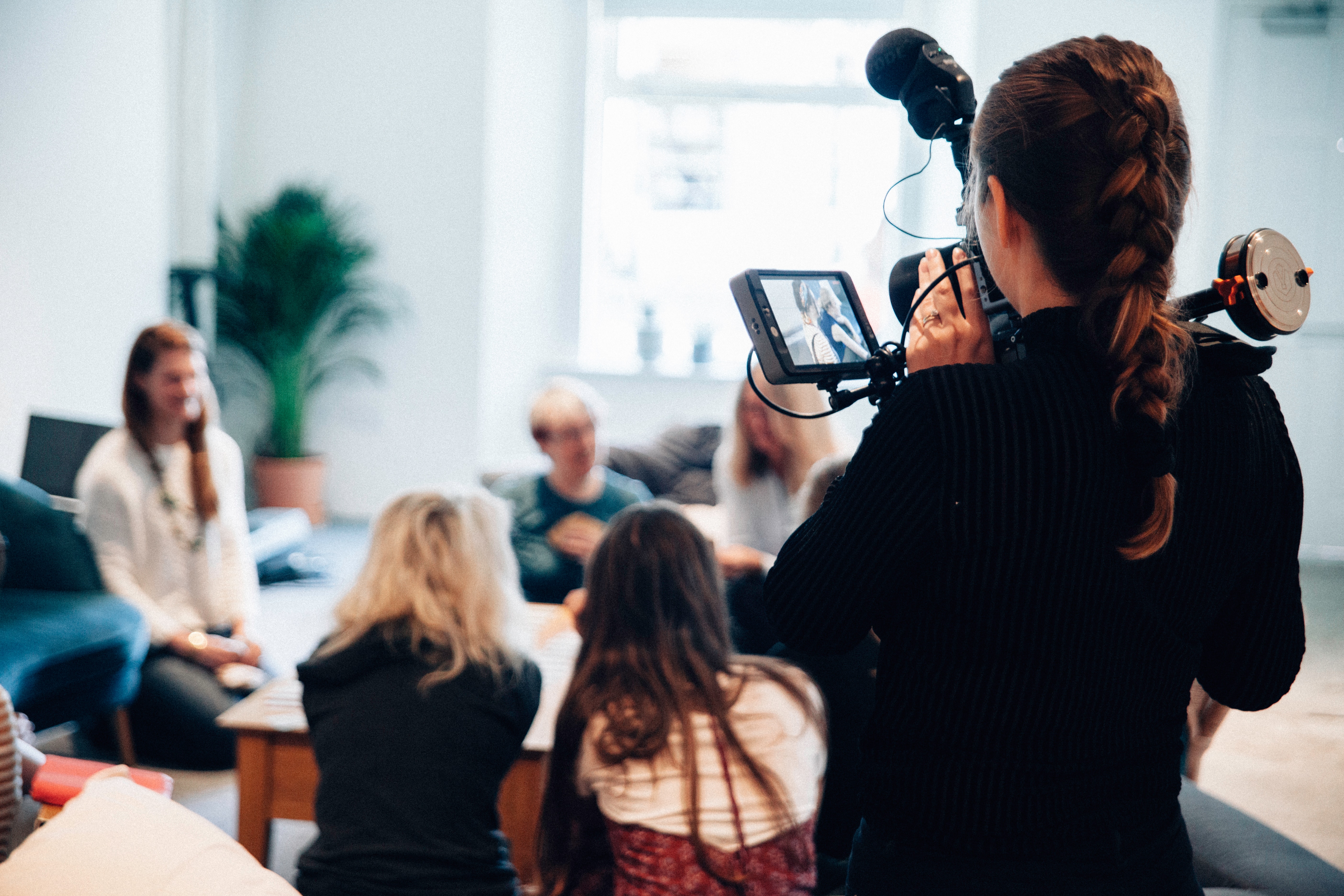 Person filmar en grupp med människor. Filmkameran är i fokus.