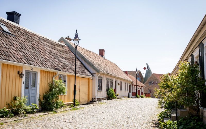 Gult gammalt trädhus längs kullerstensgata i Gamla stan i Falkenberg.