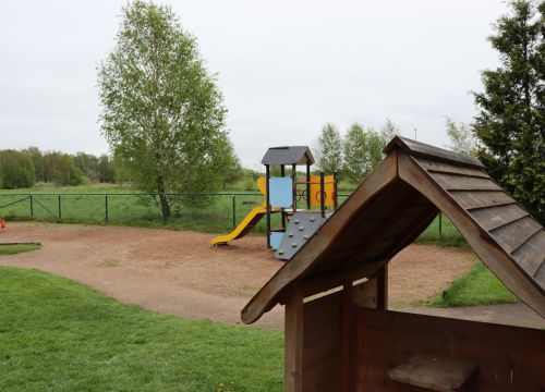 Lekstuga i trä med klätterställning i bakgrunden