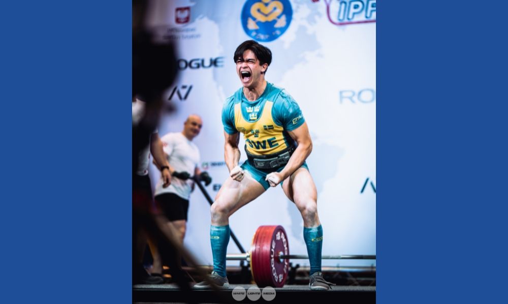 Carl med skivstång på golvet och utrycker vinnarglädje.