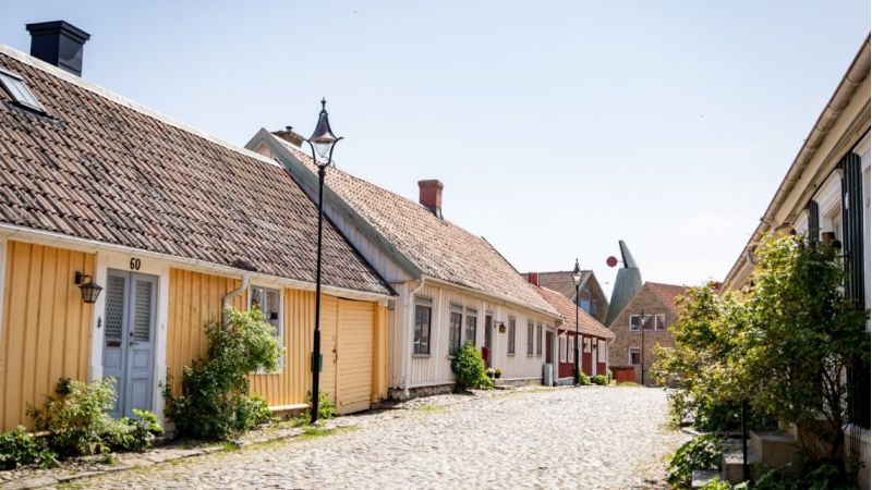 Gult gammalt trädhus längs kullerstensgata i Gamla stan i Falkenberg.