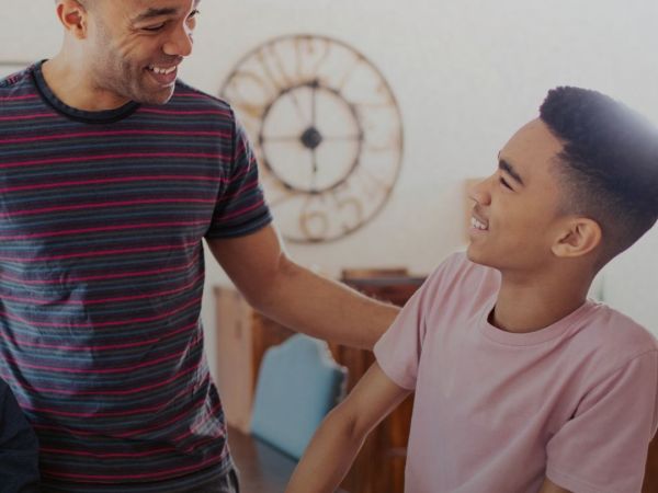 Bild på en man och en tonårspojke som ler mot varandra.