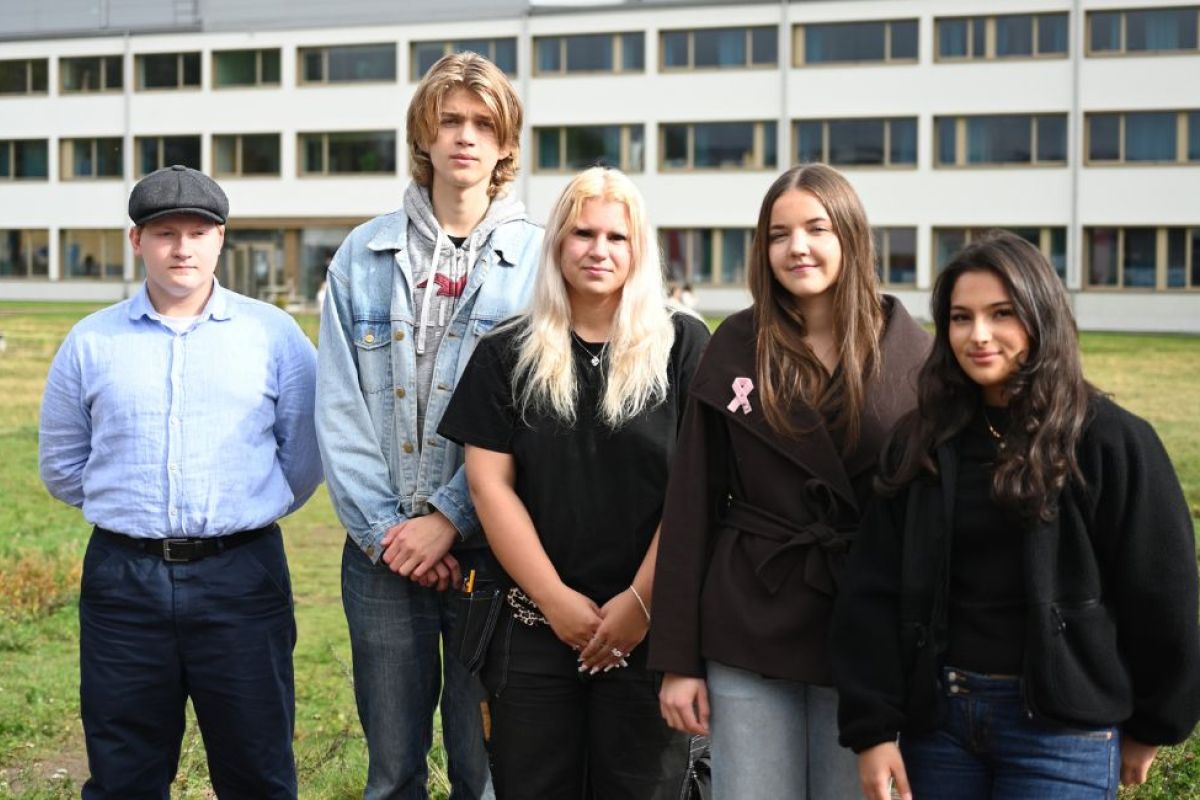 Fem elever står utomhus. I bakgrunden syns Falkenbergs gymnasieskola.