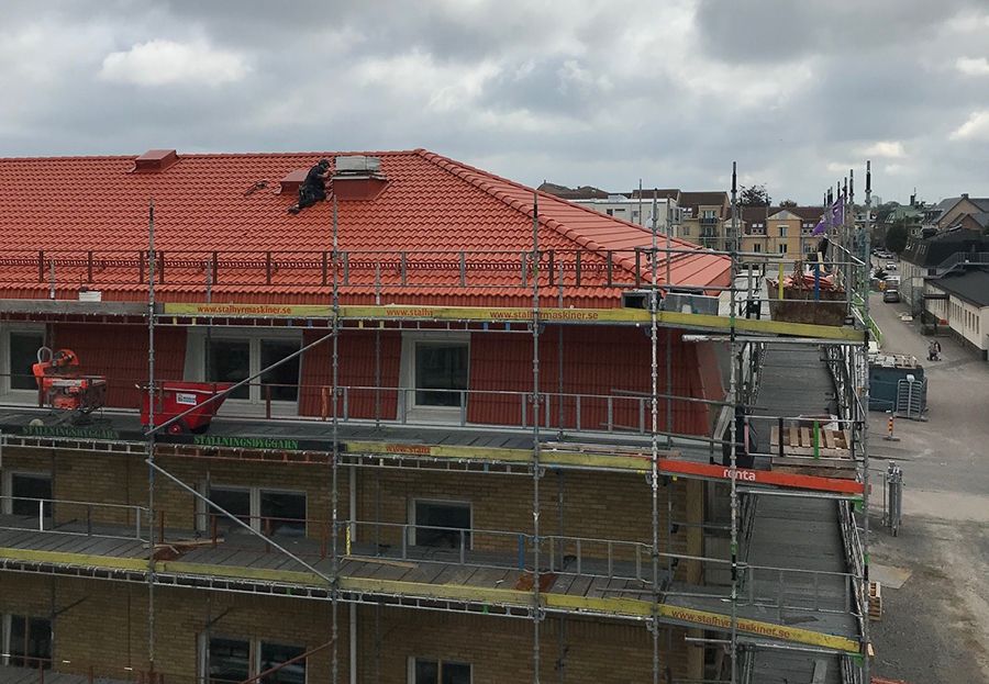 En gul tegelfastighet med byggställningar runt om. På taket ligger nya, orange tegelpannor.