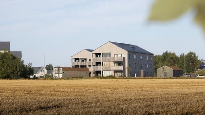 Byggnaden i sin helhet – brun och lång och mycket grönt gräs.