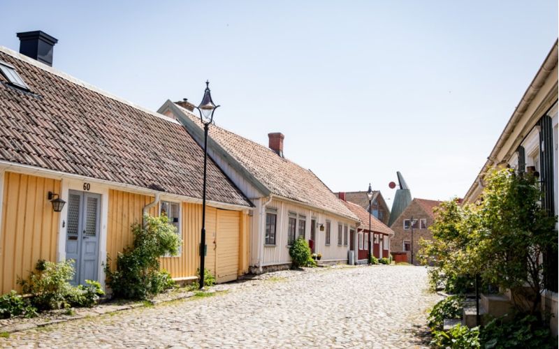 Gult gammalt trädhus längs kullerstensgata i Gamla stan i Falkenberg.