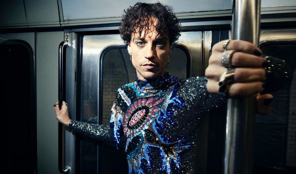 Kristofer Greczula står i en tunnelbanevagn och har på sig en glittrig topp. Han tittar in i kameran med alvarlig min,