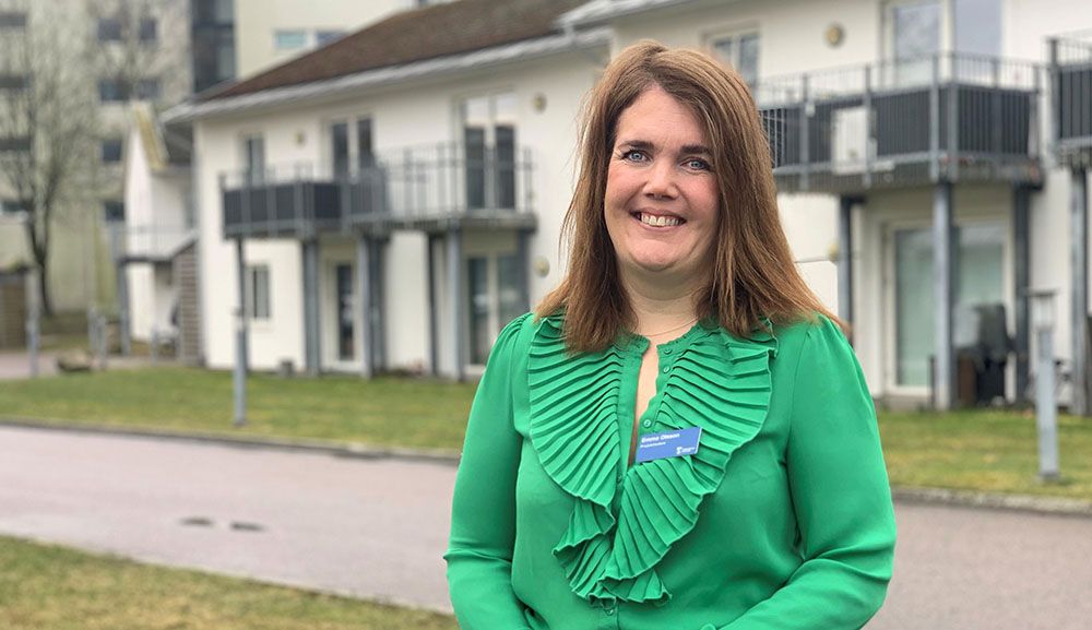 Leende kvinna med brunt hår och en grön blus.