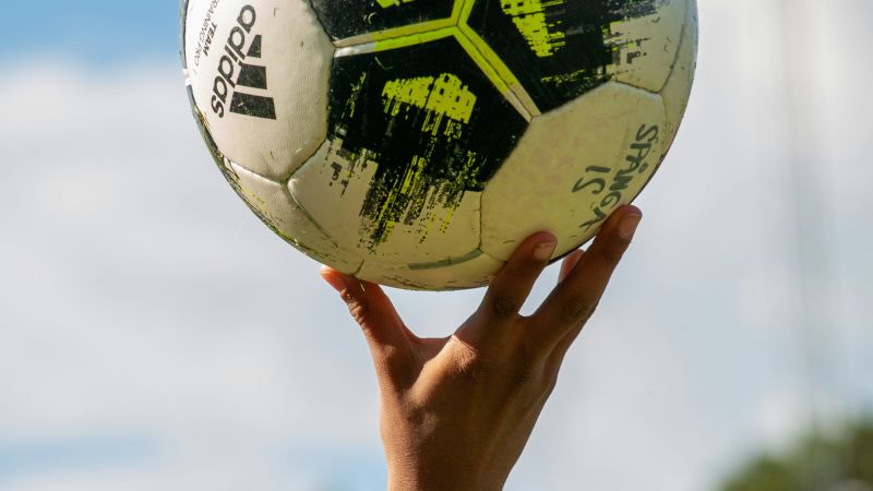 Bild på barns hand som lyfter upp en fotboll.